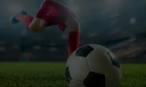 Noga piłkarza w czerwonych spodenkach i getrach kopie piłkę na tle stadionu. Nawet starzy piłkarze potrafią wzbudzić emocje.