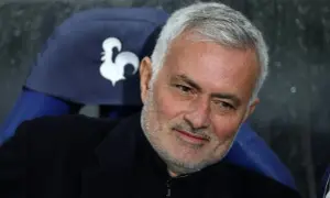 Jose Mourinho, były trener Realu Madryt, z siwymi włosami i zarostem, siedzi na ławce z symbolem koguta.
