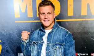 Uśmiechnięty Alan Kwieciński, którego wiek jest często przedmiotem dyskusji, w jeansowej kurtce.