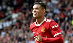 Cristiano Ronaldo w czerwonej koszulce Manchesteru United, z charakterystyczną fryzurą 2023, pokazuje kciuk w górę i wystawia język.