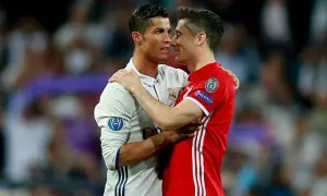 Dwóch piłkarzy, Cristiano Ronaldo i Robert Lewandowski, przytulają się. Lewandowski, z jego złotym butem, wydaje się być w dobrym nastroju.