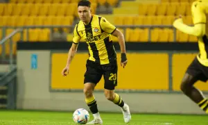 Piłkarz w żółto-czarnej koszulce, numer 28, z piłką przy nodze. Jego postawa sugeruje, że jest gotowy do akcji jako defensywny pomocnik.