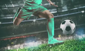 Piłkarz w akcji, jak legenda futbolu, kopie piłkę na tle stadionu.