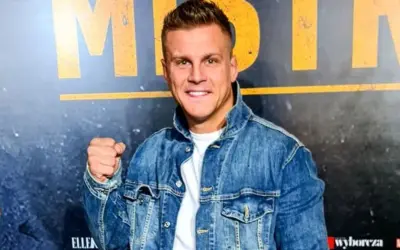 Uśmiechnięty Alan Kwieciński, którego wiek jest często przedmiotem dyskusji, w jeansowej kurtce.