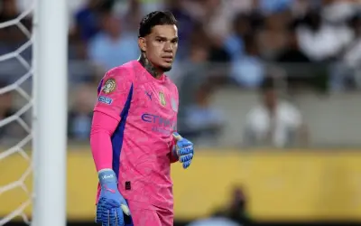 Bramkarz Manchester City w różowym stroju, gotowy do obrony bramki.