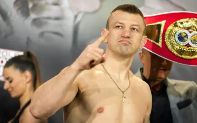 Adamek, znany z kariery bokserskiej, pokazuje swój pas mistrzowski, gotowy na walkę w świecie fame MMA.