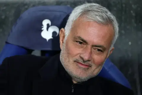 Jose Mourinho, były trener Realu Madryt, z siwymi włosami i zarostem, siedzi na ławce z symbolem koguta.