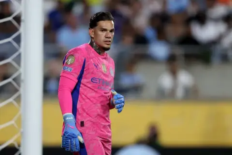 Bramkarz Manchester City w różowym stroju, gotowy do obrony bramki.