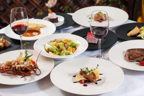 Elegancka kolacja w stylu dania francja: homar, steki, sałatka Cezar i desery, wszystko podane z czerwonym winem.