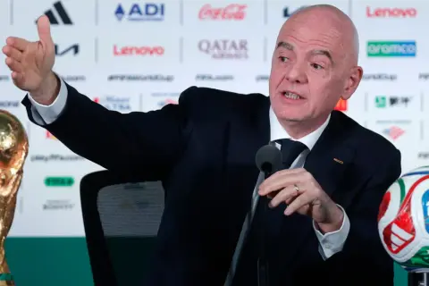 Prezydent FIFA, Gianni Infantino, gestykuluje podczas konferencji prasowej obok Pucharu Świata i piłki.