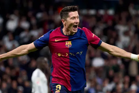 Robert Lewandowski w barwach Barcelony, z otwartymi ramionami, świętuje bramkę. Więcej informacji o jego karierze znajdziesz tutaj.