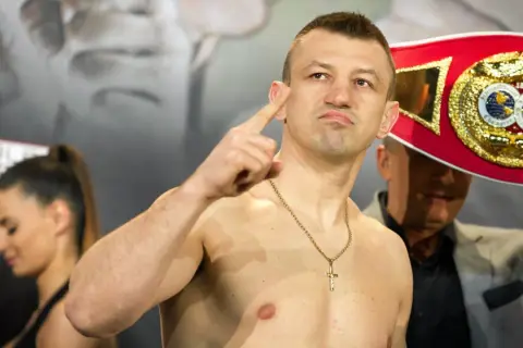 Adamek, znany z kariery bokserskiej, pokazuje swój pas mistrzowski, gotowy na walkę w świecie fame MMA.