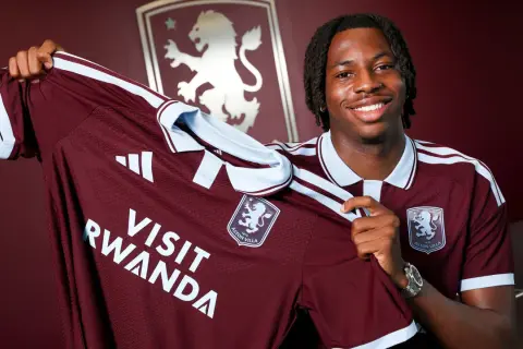 Uśmiechnięty piłkarz prezentuje nową koszulkę Aston Villa z napisem "Visit Rwanda". To ekscytujące wieści o aston villa transfery!
