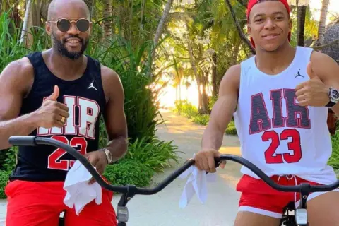 Brat Kyliana Mbappé, Ethan, w czarnej koszulce i czerwonych spodenkach, pozuje do zdjęcia z bratem, Kylianem, w białej koszulce i czerwonych spodenkach.