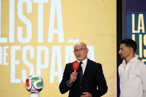 Mężczyzna w garniturze ogłasza hiszpania powołania, obok stoi piłkarz. Na ekranie w tle napis "LISTA DE ESPAÑA".