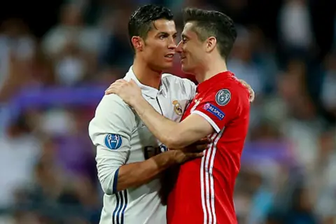 Dwóch piłkarzy, Cristiano Ronaldo i Robert Lewandowski, przytulają się. Lewandowski, z jego złotym butem, wydaje się być w dobrym nastroju.