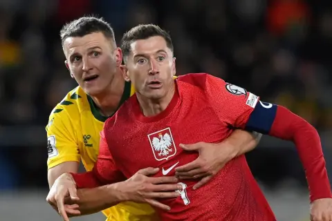 Robert Lewandowski, kapitan Polski, w czerwonej koszulce z orłem, walczy o piłkę z przeciwnikiem.