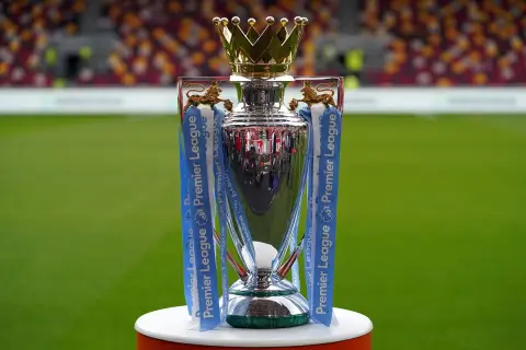Trofeum Premier League, symbol mistrzostwa Anglii, lśni na tle zielonej murawy i trybun stadionu.