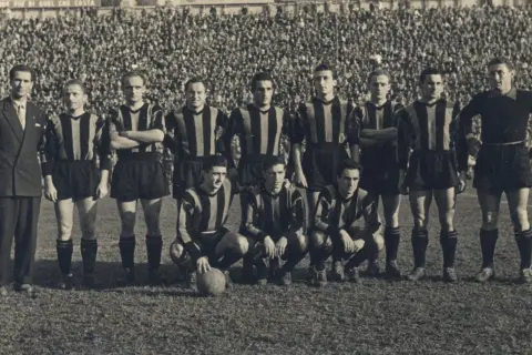 Drużyna Atalanty w historycznych strojach, gotowa do gry. W tle tłum kibiców. To zdjęcie przypomina o dawnych **atalanta transfery** i legendach klubu.