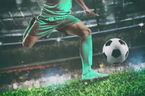 Piłkarz w akcji, jak legenda futbolu, kopie piłkę na tle stadionu.