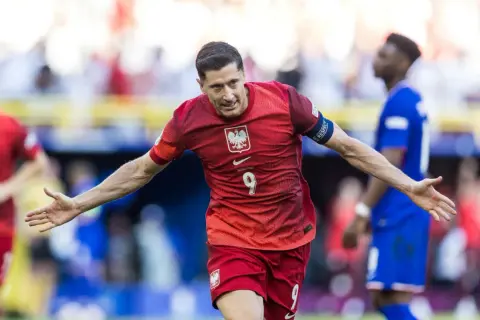 Robert Lewandowski cieszy się po strzelonym karnym. Piłkarz w czerwonej koszulce z numerem 9 świętuje zwycięstwo.