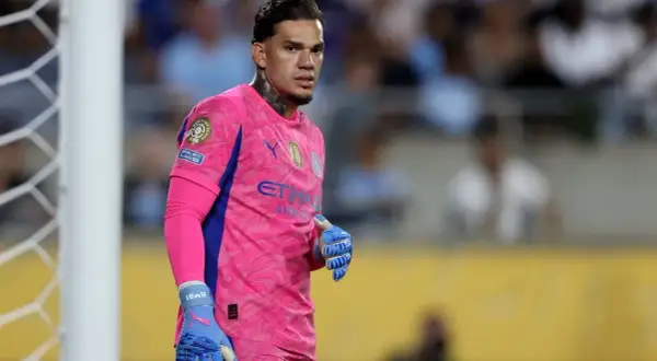 Bramkarz Manchester City w różowym stroju, gotowy do obrony bramki.