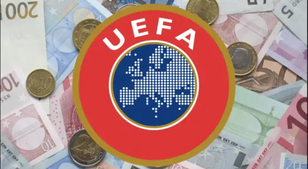 Logo UEFA na tle banknotów i monet euro. Symbolizuje finansowe fair play w europejskiej piłce nożnej.