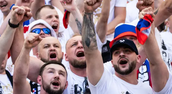 Tłum kibiców w barwach Górnika Zabrze, z uniesionymi pięściami i okrzykami radości.