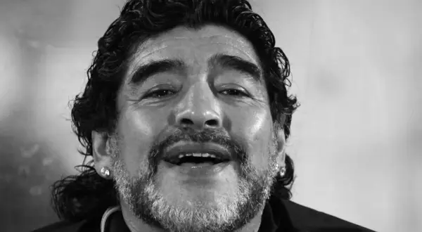 Uśmiechnięty Diego Maradona, którego zdjęcie budzi pytania: czy Diego Maradona żyje? Ikona futbolu z charakterystyczną fryzurą i zarostem.