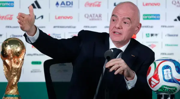 Prezydent FIFA, Gianni Infantino, gestykuluje podczas konferencji prasowej obok Pucharu Świata i piłki.