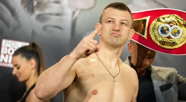 Adamek, znany z kariery bokserskiej, pokazuje swój pas mistrzowski, gotowy na walkę w świecie fame MMA.