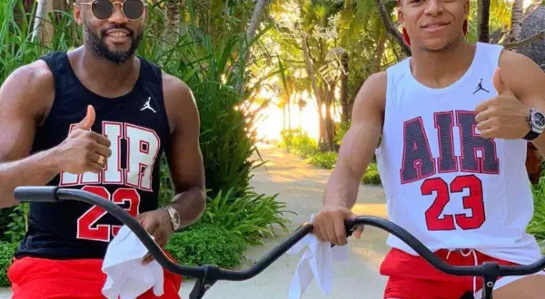 Brat Kyliana Mbappé, Ethan, w czarnej koszulce i czerwonych spodenkach, pozuje do zdjęcia z bratem, Kylianem, w białej koszulce i czerwonych spodenkach.