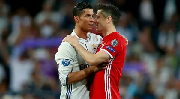 Dwóch piłkarzy, Cristiano Ronaldo i Robert Lewandowski, przytulają się. Lewandowski, z jego złotym butem, wydaje się być w dobrym nastroju.