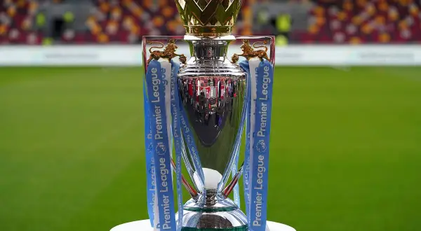 Trofeum Premier League, symbol mistrzostwa Anglii, lśni na tle zielonej murawy i trybun stadionu.