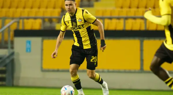 Piłkarz w żółto-czarnej koszulce, numer 28, z piłką przy nodze. Jego postawa sugeruje, że jest gotowy do akcji jako defensywny pomocnik.
