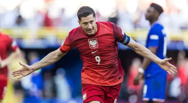 Robert Lewandowski cieszy się po strzelonym karnym. Piłkarz w czerwonej koszulce z numerem 9 świętuje zwycięstwo.