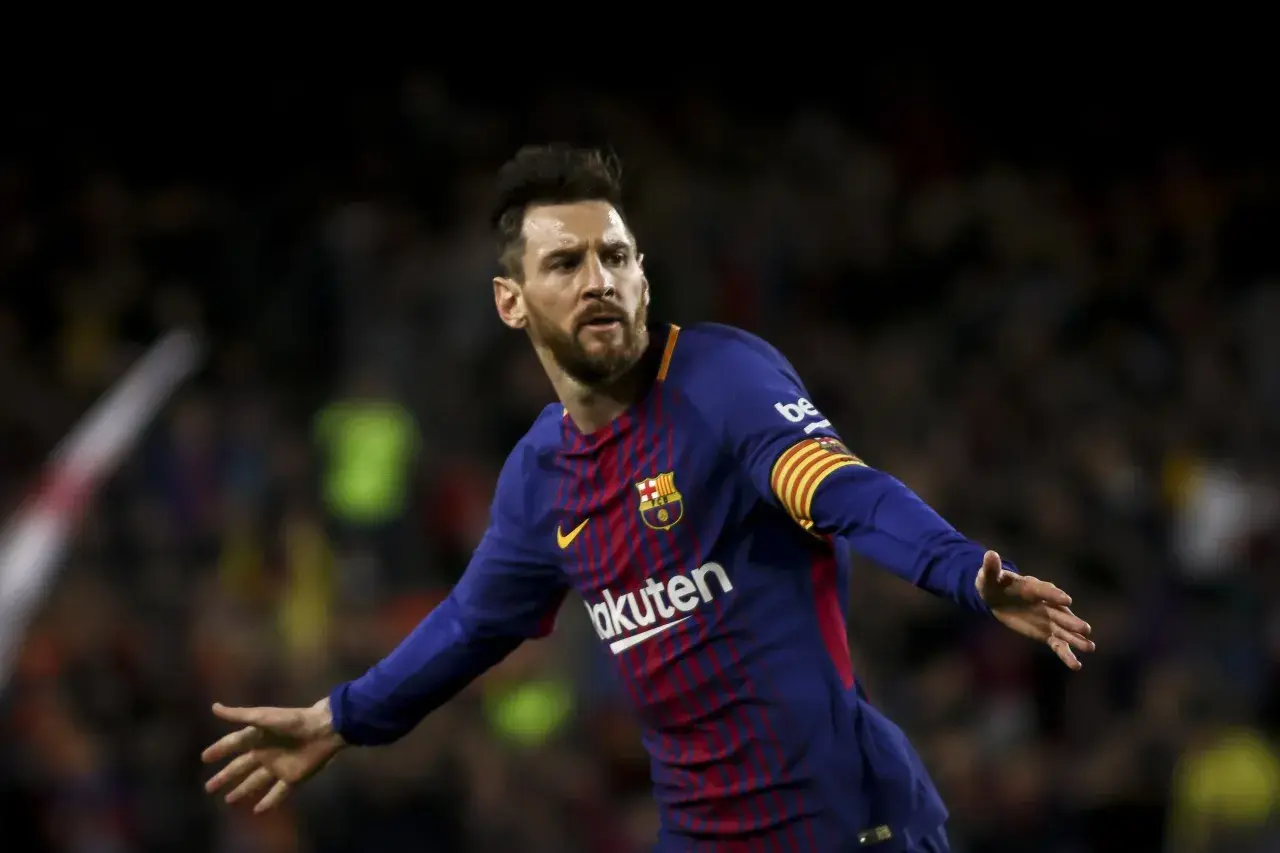 Piłkarz FC Barcelona, Lionel Messi, w niebiesko-bordowej koszulce z opaską kapitana na ramieniu, cieszy się z bramki.