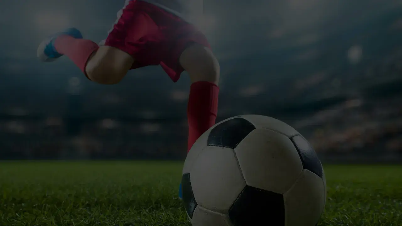 Noga piłkarza w czerwonych spodenkach i getrach kopie piłkę na tle stadionu. Nawet starzy piłkarze potrafią wzbudzić emocje.