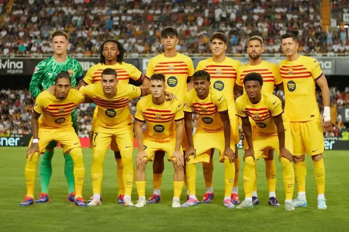 Drużyna FC Barcelona w żółtych strojach. Robert Lewandowski, który jest kapitanem Barcelony, stoi w pierwszym rzędzie.