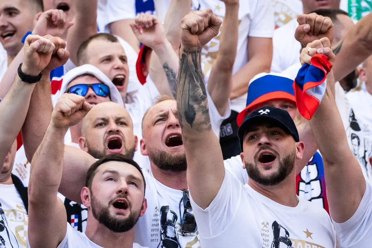 Tłum kibiców w barwach Górnika Zabrze, z uniesionymi pięściami i okrzykami radości.