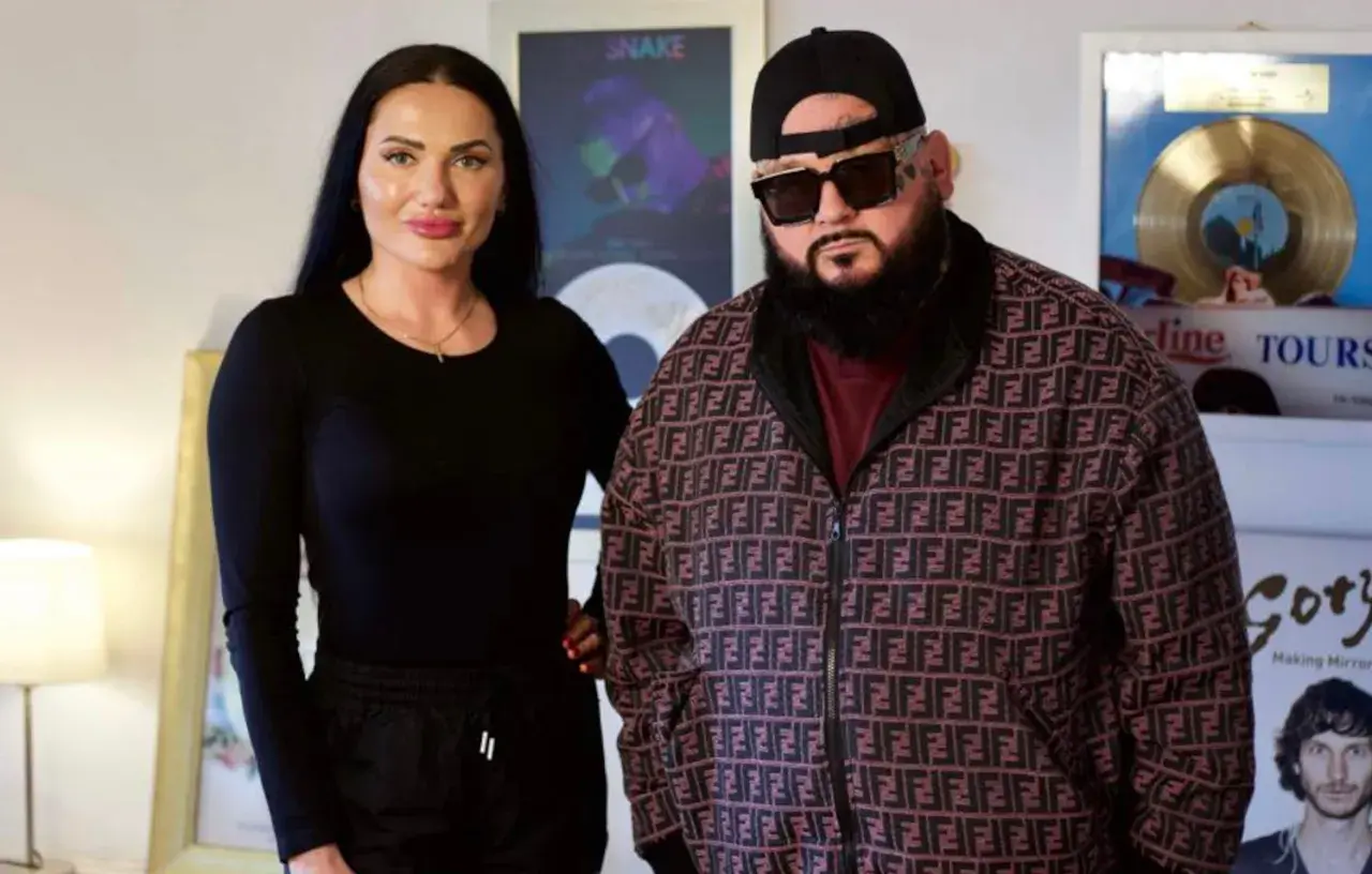 Ewa Brodnicka i jej partner pozują do zdjęcia. Ona w czarnej bluzce, on w charakterystycznej kurtce z logo.