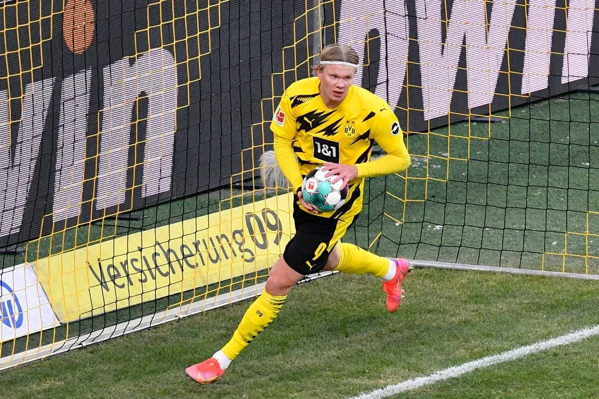 Erling Haaland w żółtej koszulce BVB z piłką, gotowy do gry. Jego daty dołączenia do klubu są kluczowe dla strategii zespołu.