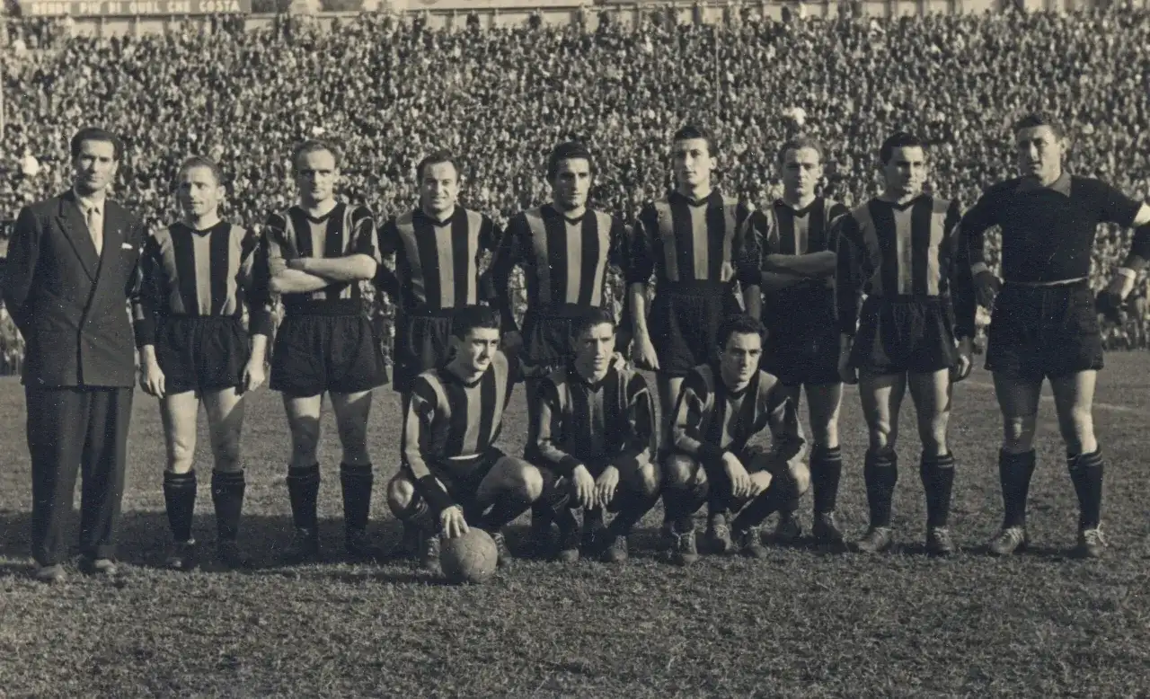 Drużyna Atalanty w historycznych strojach, gotowa do gry. W tle tłum kibiców. To zdjęcie przypomina o dawnych **atalanta transfery** i legendach klubu.