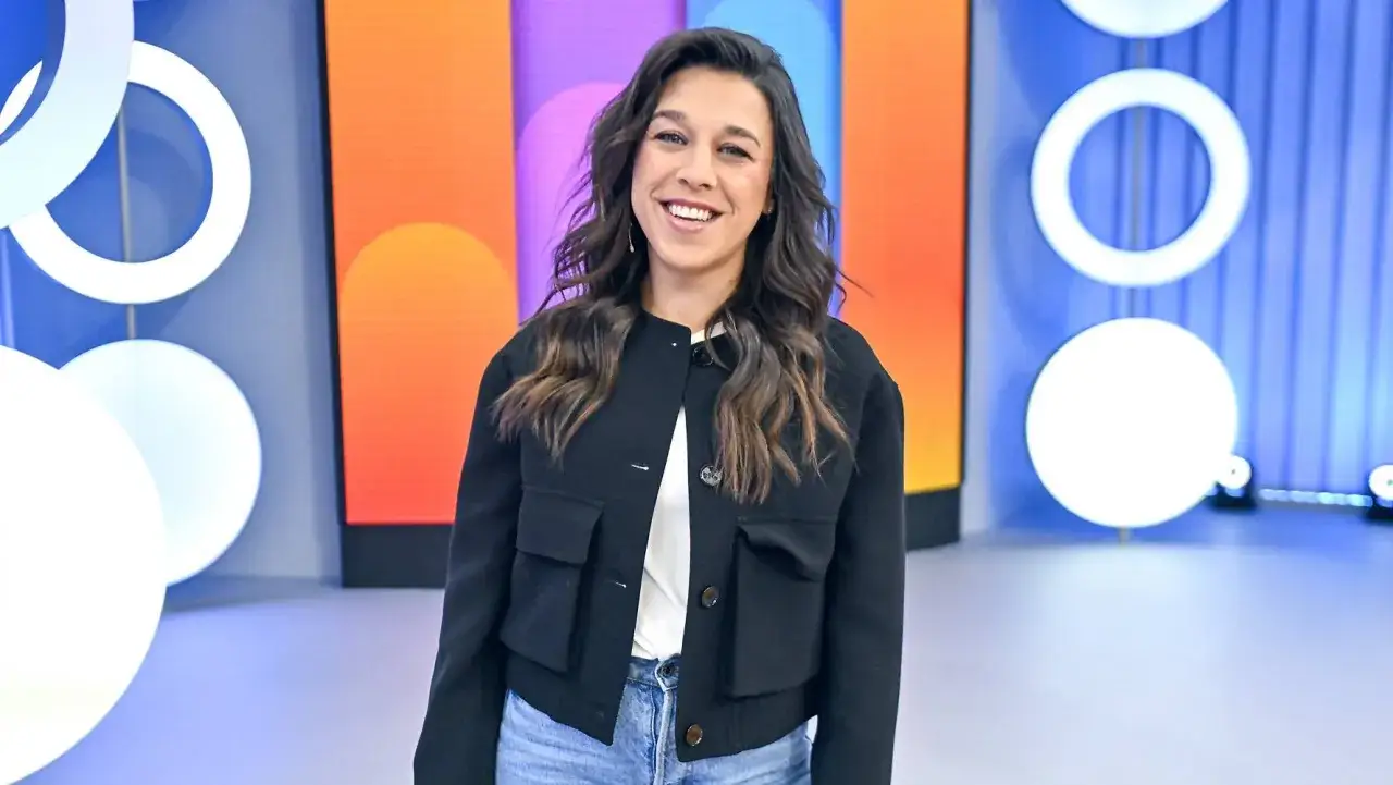 Uśmiechnięta Joanna Jędrzejczyk, której rekordy w MMA budzą podziw, pozuje na tle kolorowej scenografii.