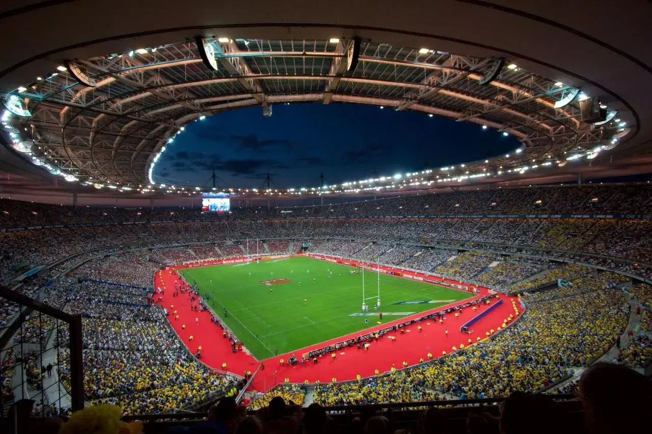 Stadion w Danii, Francja, wypełniony kibicami w żółtych i białych strojach, gotowy na mecz rugby.
