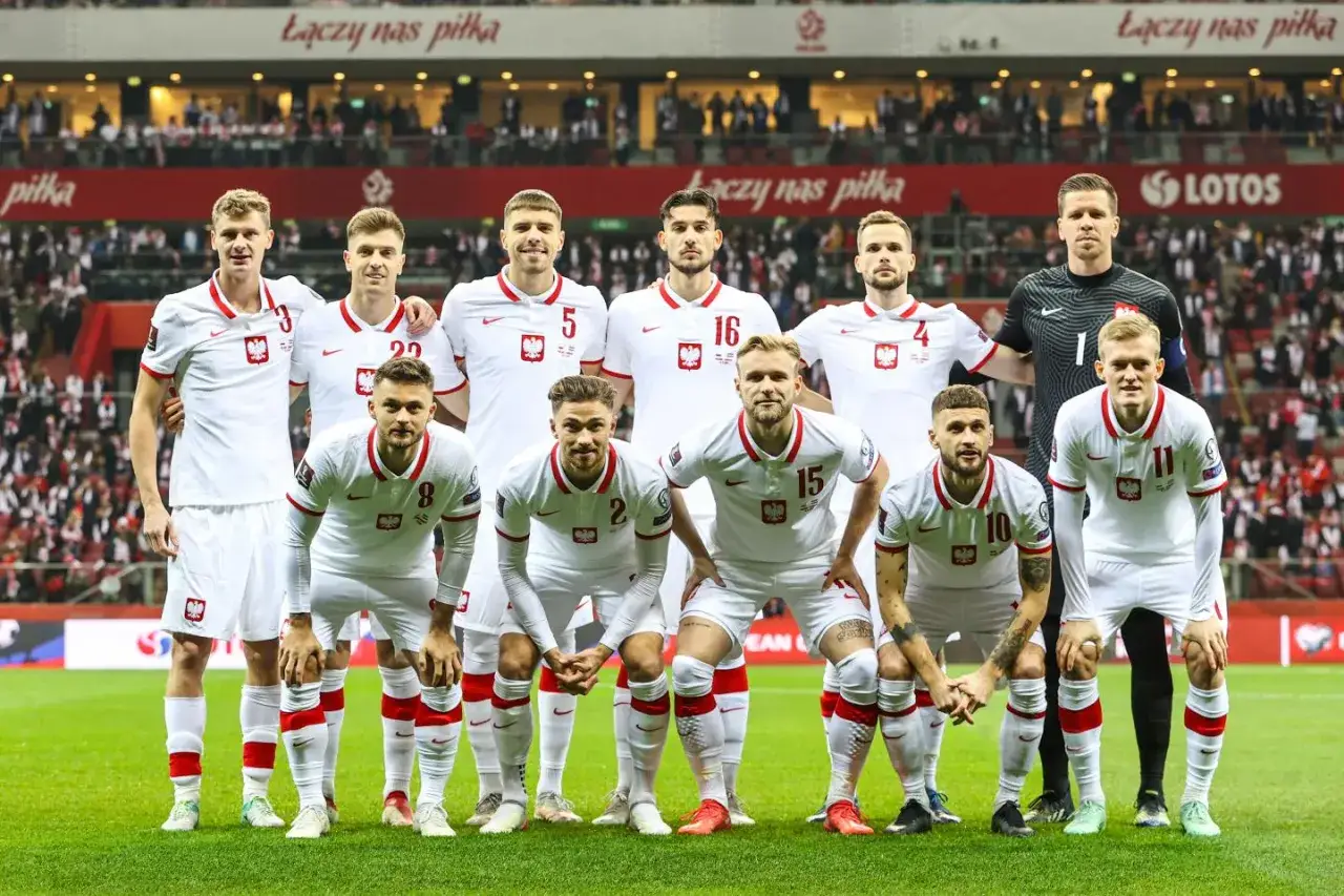 Piłkarze reprezentacji Polski w białych strojach pozują do zdjęcia. Ich determinacja zapowiada najwyższe miejsce Polski w rankingu FIFA.