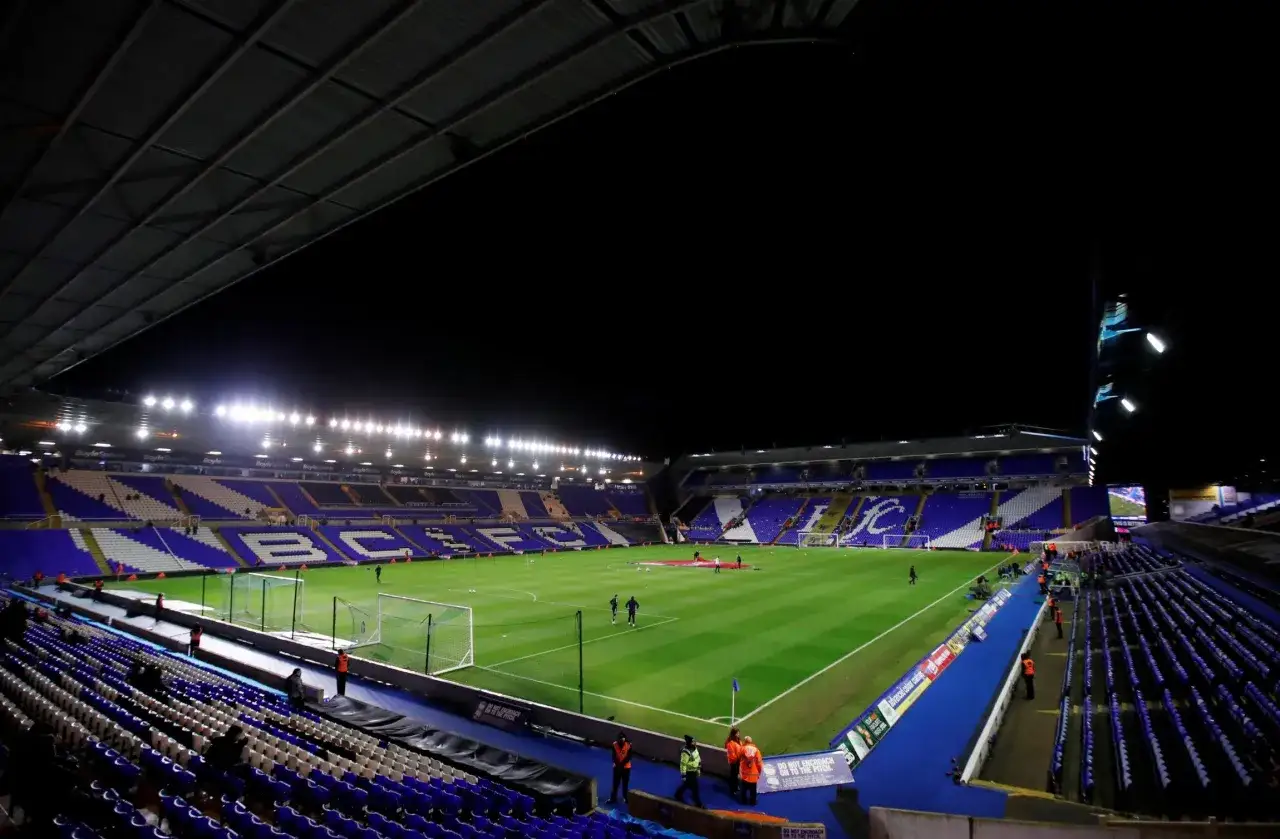 Pusta trybuna stadionu Birmingham klubu nocą, oświetlona jaskrawymi światłami.