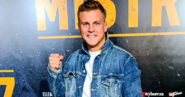 Uśmiechnięty Alan Kwieciński, którego wiek jest często przedmiotem dyskusji, w jeansowej kurtce.