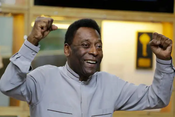 Uśmiechnięty Pelé z podniesionymi pięściami, symbol triumfu. Jego niesamowite pelé statystyki mówią same za siebie.