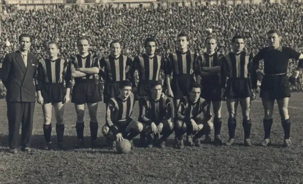 Drużyna Atalanty w historycznych strojach, gotowa do gry. W tle tłum kibiców. To zdjęcie przypomina o dawnych **atalanta transfery** i legendach klubu.